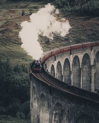 Train on bridge against mountain