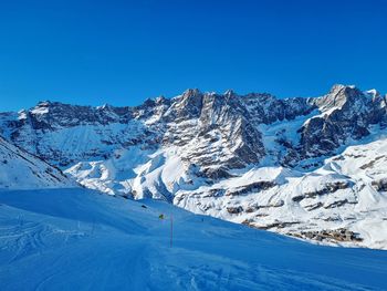 Scenic view of snowcapped mountains against clear blue sky