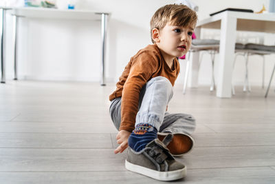 Boy sitting on wooden floor at home