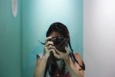 Portrait of young woman wearing sunglasses against wall