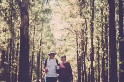 Couple standing against trees in forest