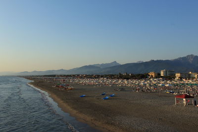 Panoramic view of crowd at beach against clear sky