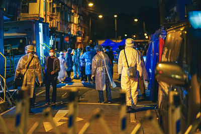 Rear view of people walking on illuminated street at night