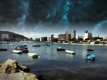 Boats in river against cloudy sky