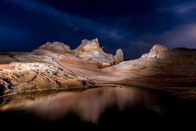 Scenic view of rocky landscape by water against sky