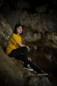 Lady hiker posing, she sit on the rock insite the cave