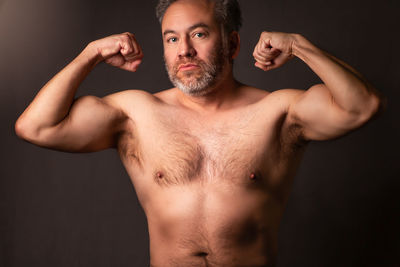 Portrait of shirtless young man against black background