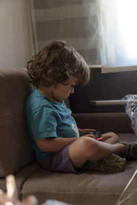 Side view of boy playing with toy at home