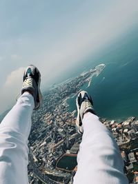 Low section of man by sea against sky