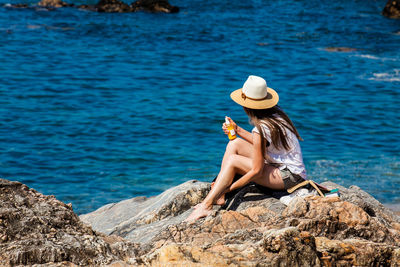 Woman sitting on rock by sea