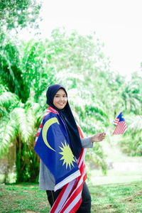 Muslim woman happy holding a malaysian flag. malaysia independence day.