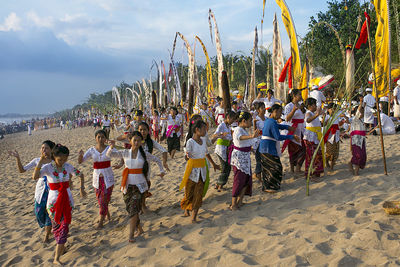 Females dancing on sand at beach during melasti festival