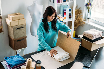 Small business owner woman packs the goods in eco packaging in office, shop.