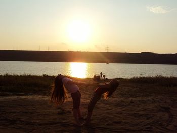 Silhouette people on beach against sky during sunset