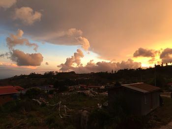 Houses on field against sky during sunset