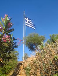 Low angle view of flag against clear blue sky