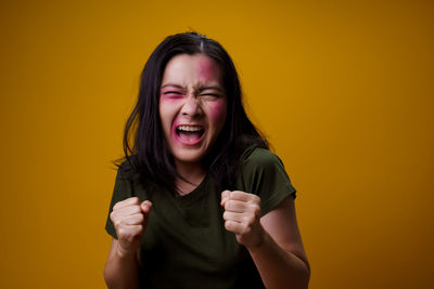 Beautiful young woman standing against yellow background