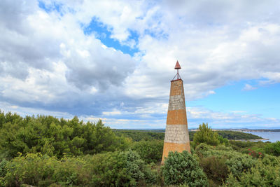 Tower on field against cloudy sky