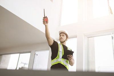 Low angle view of young man with arms raised