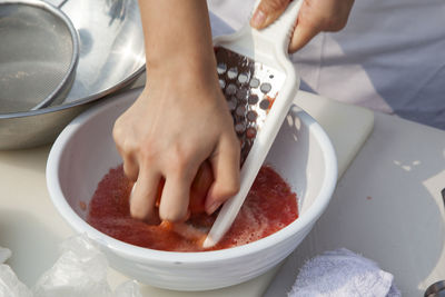 Midsection of chef grating tomato on table