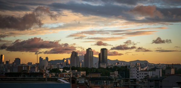 Panoramic view of cityscape against cloudy sky during sunset