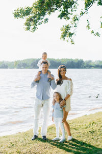Summer portrait of a beautiful young family with two children near the lake. mom, dad, son