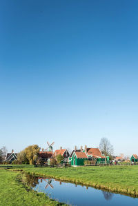 Houses on field against clear blue sky