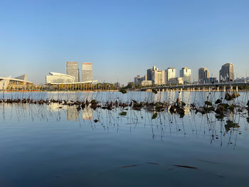 Reflection of buildings in lake against sky in city