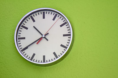 Close-up of clock on green wall