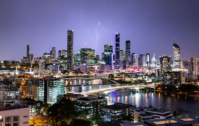 Illuminated buildings in city against sky at night