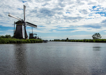 Traditional windmills by lake against sky