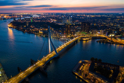 High angle view of illuminated bridge over river by buildings in city