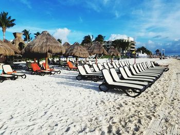 Deck chairs on beach against sky