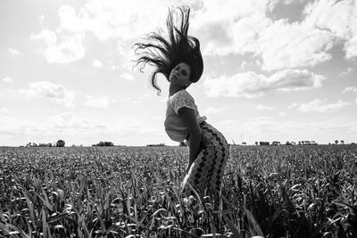 Portrait of woman tossing hair while standing amidst plants