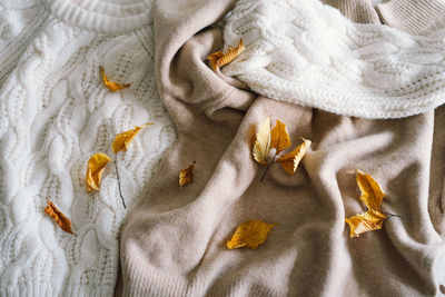 Background with warm sweaters. pile of knitted clothes with autumn leaves, warm background.