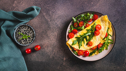 Omelette pancake with cherry tomatoes and arugula on a plate on the table top view web banner