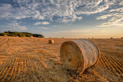 Hay bales on field against sky