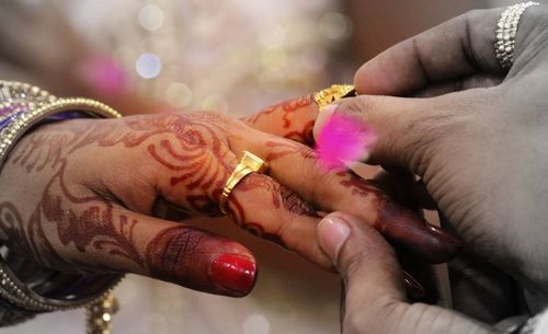 Cropped image of groom inserting wedding ring in bride finger during ceremony