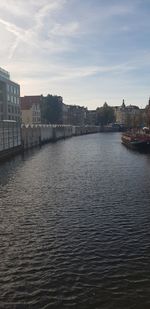 River by buildings in city against sky