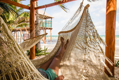 Bare legs and feet of a young girl lounging in a hammock at a beach at the riviera maya, mexico