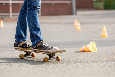 Low section of man skateboarding on road