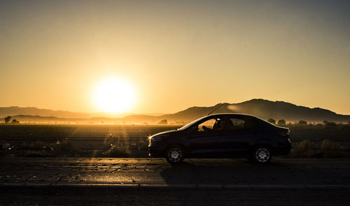 Car on road against sky during sunset