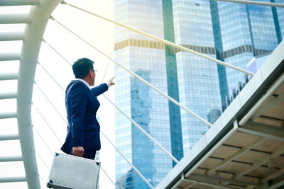 Low angle view of man standing by glass building