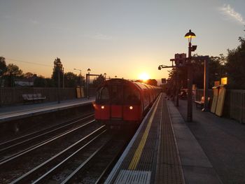 Train at railroad station against sky during sunset