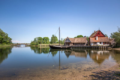 Scenic view of river by buildings against clear blue sky