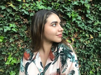 Young woman looking away against plants