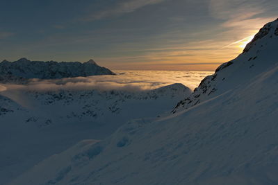 Scenic view of snow covered mountains against sky during sunset