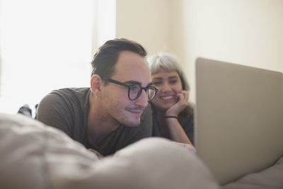 Young couple lying in bed looking at a laptop