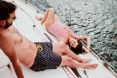 Shirtless man and woman on boat sailing in sea
