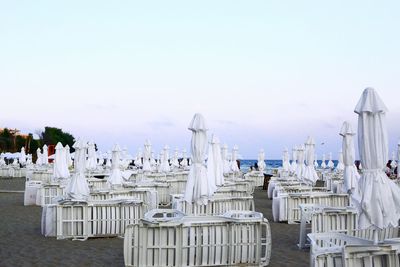 White lounge chairs with umbrellas at beach against clear sky at dusk